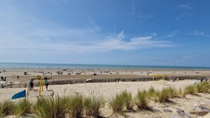 A beach with a wooden fence, a goalpost, and people in the distance. - ESCAL'HOTEL (Etaples)