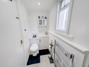 A compact, well-lit bathroom with a toilet, sink, and storage cabinet. - Apartment-sleeps6-parking-internet (London)