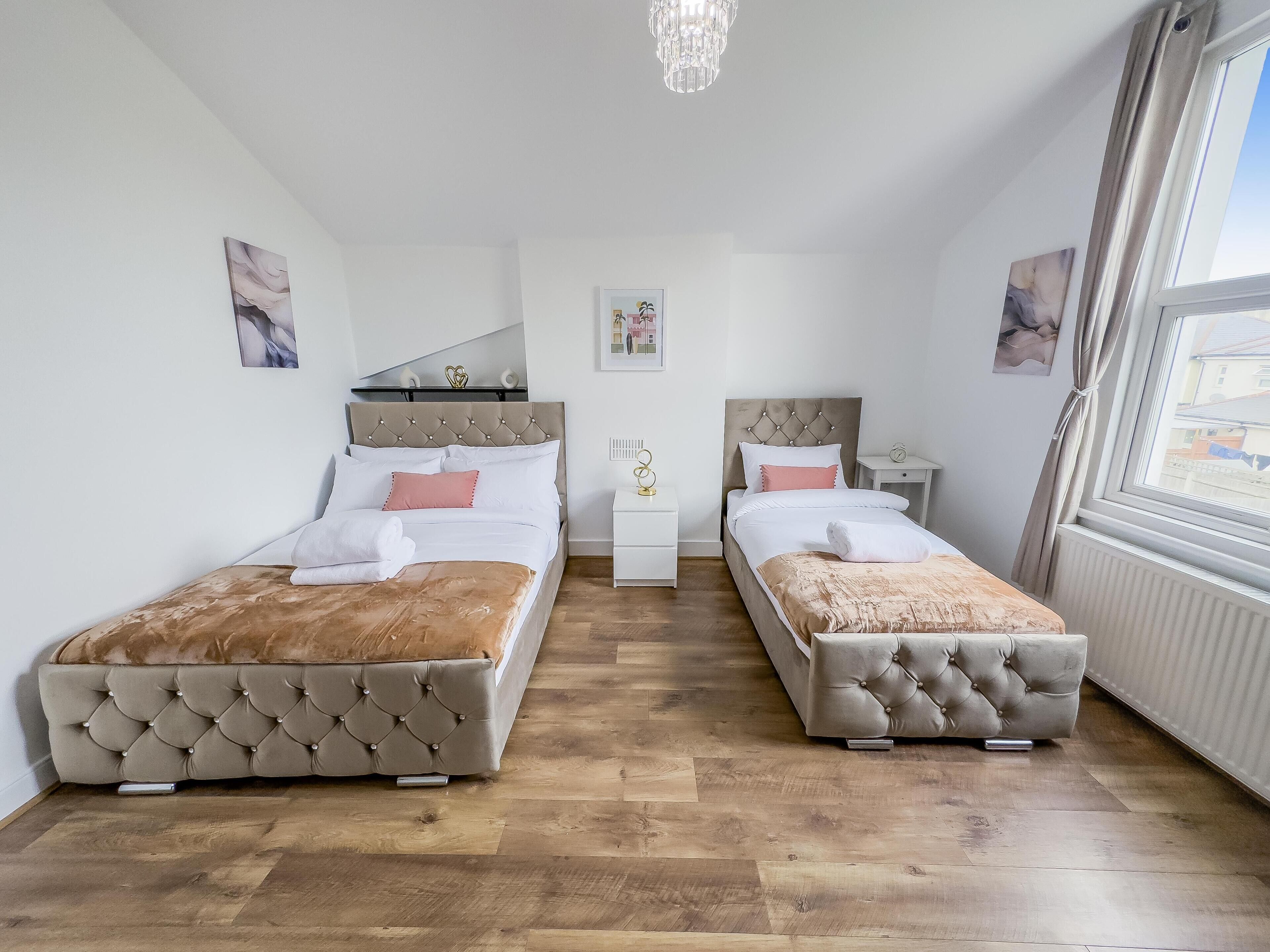 Ein Schlafzimmer mit zwei Betten, einer Kristallleuchter und Blick ins Freie.