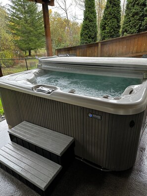 A hot tub with a wooden deck and steps leading up to it, surrounded by a wooden fence and trees. - Private Hot Tub, Charming 1-bedroom apartment in delightful Vancouver with WiFi (Vancouver)