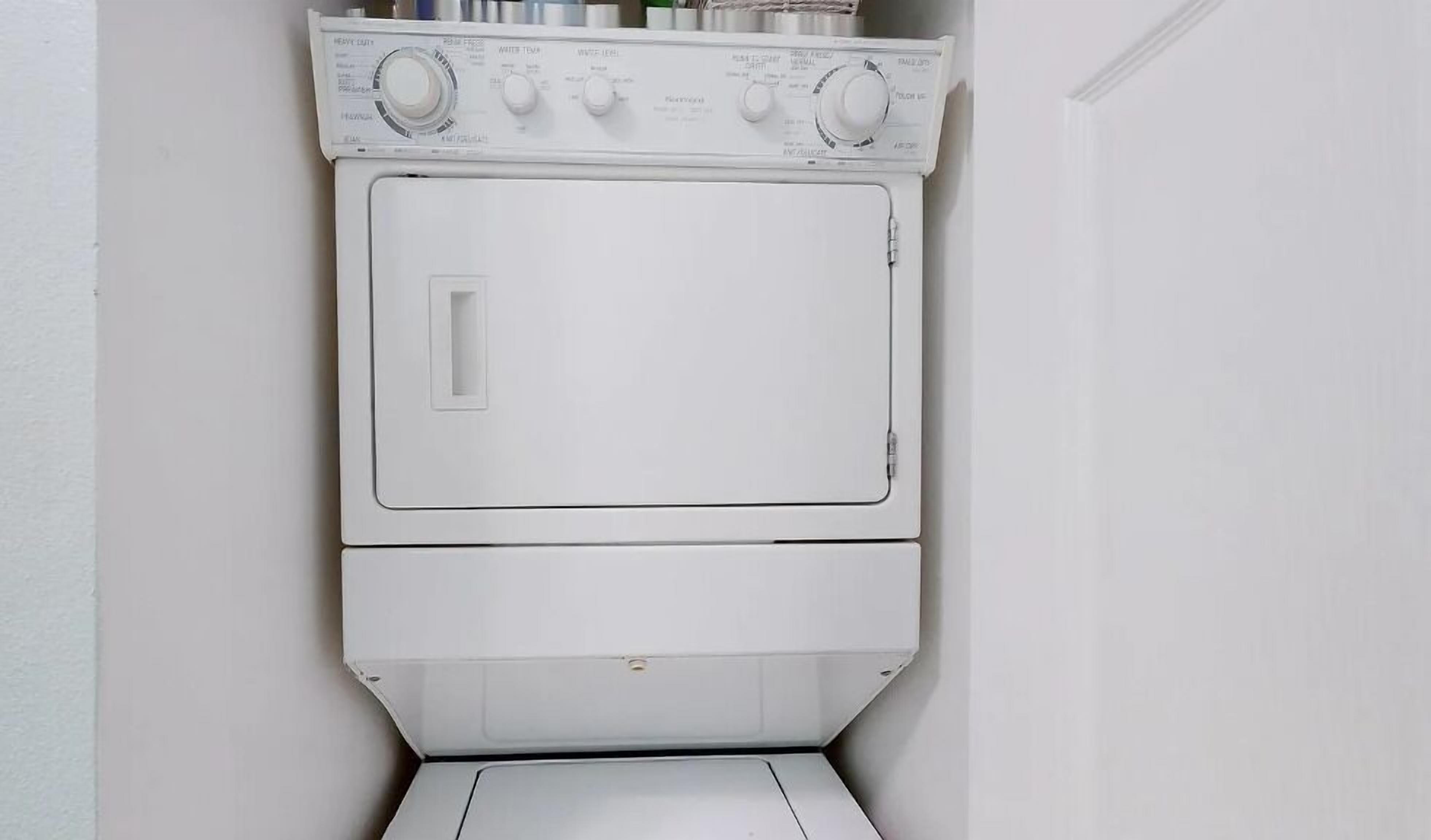 A white, wall-mounted, front-loading washer and dryer unit with control knobs and a door.