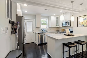 A modern kitchen with stainless steel appliances, a central island, bar stools, and pendant lighting. - 2BR DC Retreat - Near Metro - Free Street Parking (Washington)