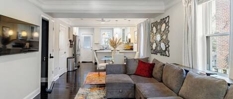 Un salon moderne avec un canapé d’angle, une table basse et un miroir décoratif.