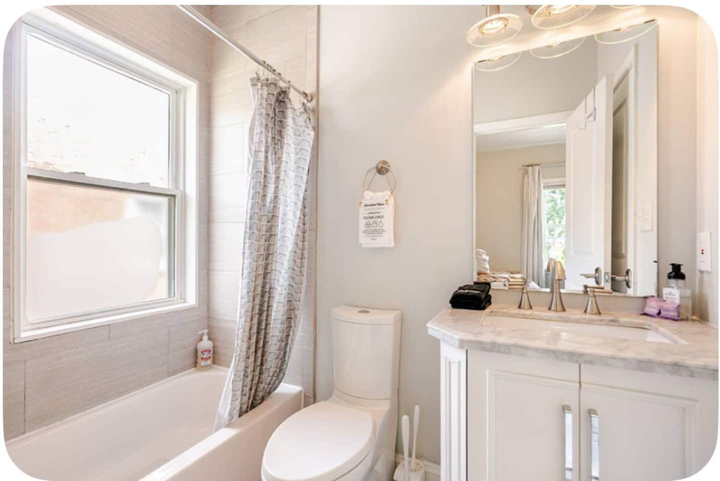 A bathroom with a bathtub, toilet, and vanity with a mirror.