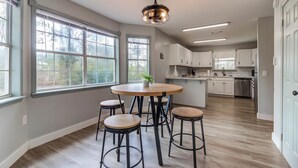 A spacious kitchen with large windows, a central island, and bar stools.
