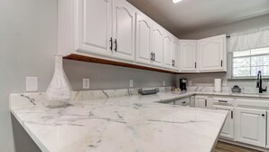 A kitchen with white cabinetry, marble countertops, and a built-in oven.