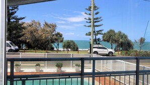 A pool area with a view of the ocean and parked cars. - Capricorn Pacific - 2 Bedroom, 2 bathroom apartment with Ocean views (Bargara)