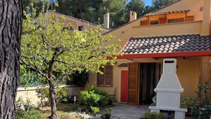 A courtyard with two wooden chairs, a stone bench, and a white stone structure.