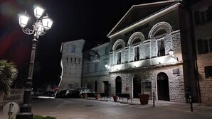 A historic building with a stone facade and arched windows, illuminated by street lamps.