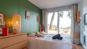 Una camera da letto con un letto, una cassettiera, una lampada e vista sull'esterno.