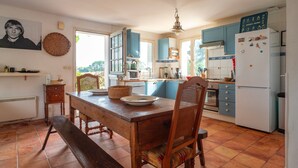 Una cucina con un tavolo di legno, sedie, un frigorifero e pensili blu.