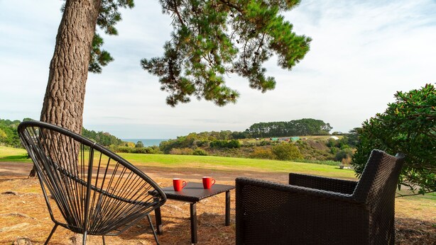 Un'area salotto esterna con una sedia, un tavolo, un albero e vista sul paesaggio.