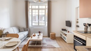 Una sala de estar moderna con sofá, mesa de comedor y zona de cocina.