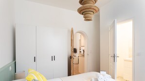 Habitación de hotel con cama, armario, espejo y puerta que da a un baño.