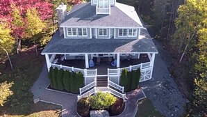 A large, two-story house with a wrap-around porch, surrounded by trees and a well-maintained lawn.