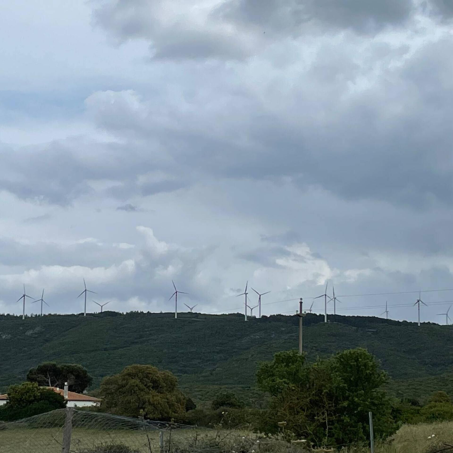 A landscape with multiple wind turbines on a hill.