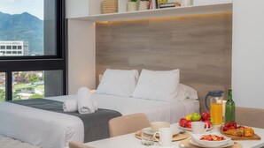 Une chambre d’hôtel avec un lit, une table pour le petit-déjeuner et une vue sur les montagnes.