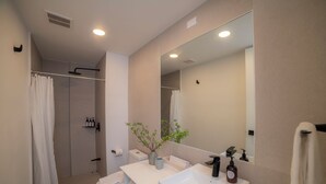 Une salle de bain moderne équipée d’une douche, de toilettes, d’un lavabo et d’un miroir.