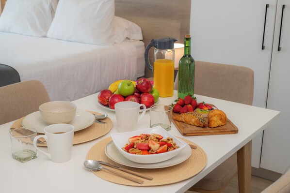 A breakfast table with fruits, a jug of orange juice, a bottle, and a croissant. - Apartment in the gastronomic zone, San José, Barrio Escalante (San José, Carmen)