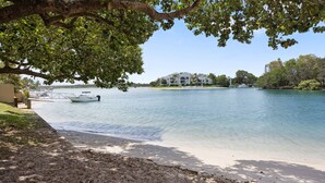 A waterfront property with a boat dock, sandy beach, and a building with multiple floors.