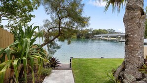 A backyard with a wooden deck, a small pond, and a bridge in the background.