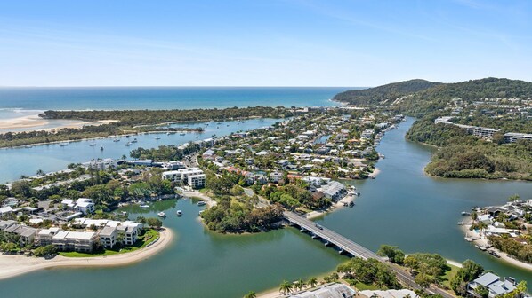 An aerial view of a coastal residential area with a marina, houses, and a bridge connecting two parts of the community.