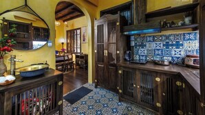 A kitchen with a blue and white tiled backsplash, wooden cabinets, and a large mirror above the sink.