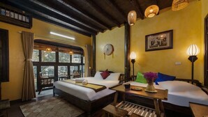 A room with two beds, a wooden table, and a window with curtains.