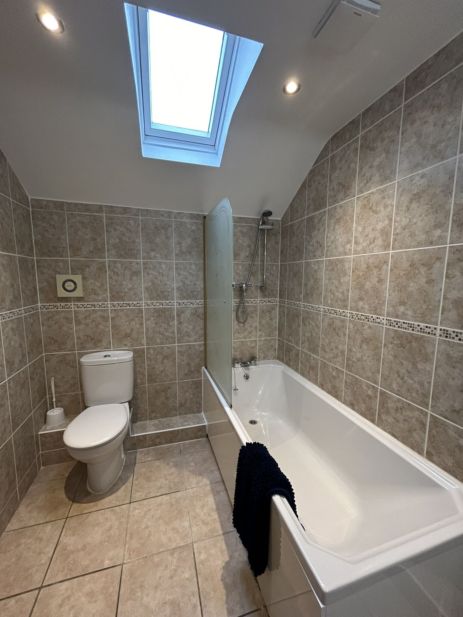 Ein Badezimmer mit Dachfenster, Badewanne, Toilette und Dusche.