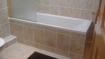 Un baño con bañera, inodoro y zona de ducha.