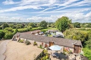A large, rustic building with a tiled roof, surrounded by a gravel driveway and a well-maintained garden. - Golden Fleece (Chard)