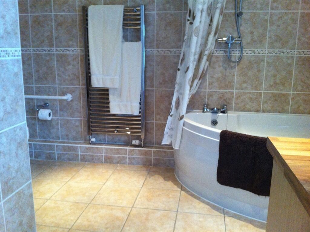 A bathroom with a bathtub, a towel rack, and a shower curtain.