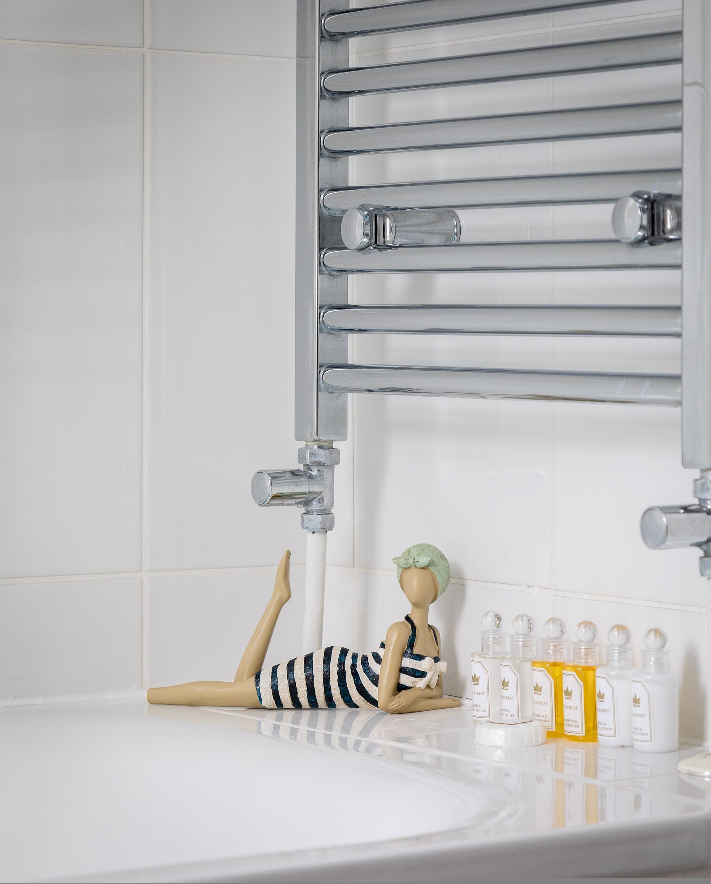 Ein Badezimmer mit einer Badewanne, einem Handtuchhalter und einer dekorativen Mannequin.