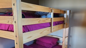 A bunk bed with purple bedding in a room with wooden flooring.