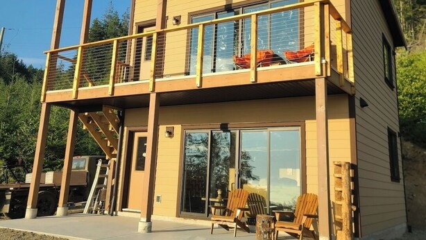 A two-story building with a balcony, large windows, and outdoor seating.