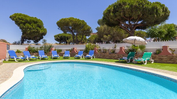 Ein Swimmingpool mit blauem Wasser, umgeben von blauen Liegestühlen und einem weißen Zaun.