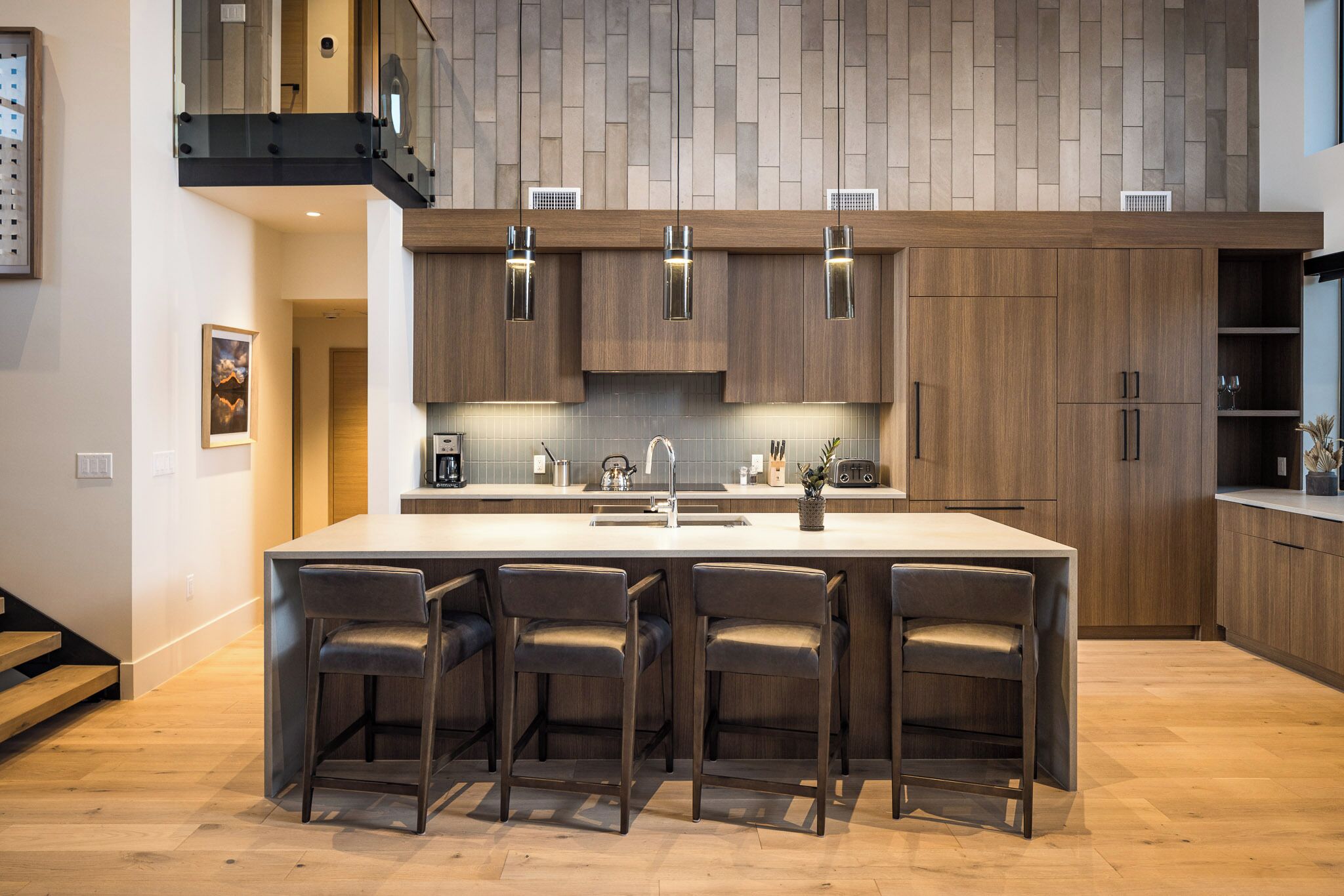 A modern kitchen with a large island, wooden cabinets, and bar stools.