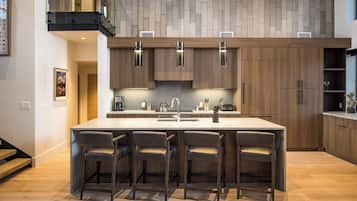 A modern kitchen with a large island, wooden cabinets, and bar stools.