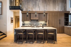 Una cocina moderna con una isla grande, armarios de madera y taburetes de bar.