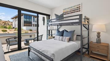 A modern bedroom with a bunk bed, a desk, and a chair, featuring a large window and a view of a building.