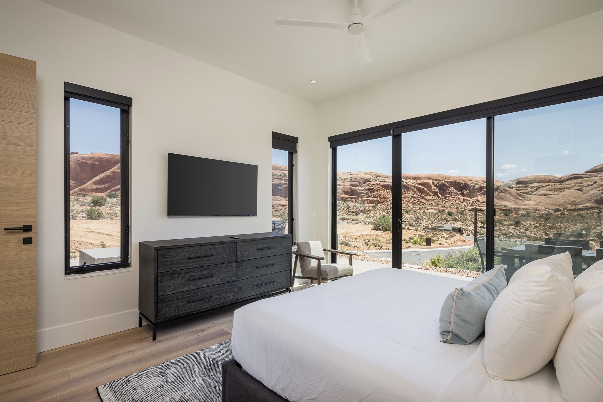 A bedroom with a large bed, a flat-screen TV, a dresser, and a chair.