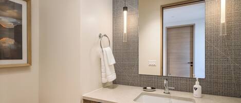 A modern bathroom with a large mirror, a sink, and a towel rack.
