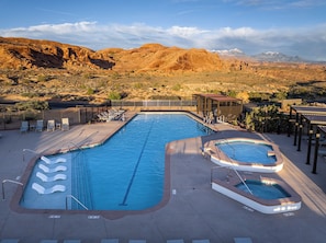 A swimming pool with lounge chairs and a hot tub, surrounded by a desert landscape with mountains in the background. - Lionsback Resort (Moab)