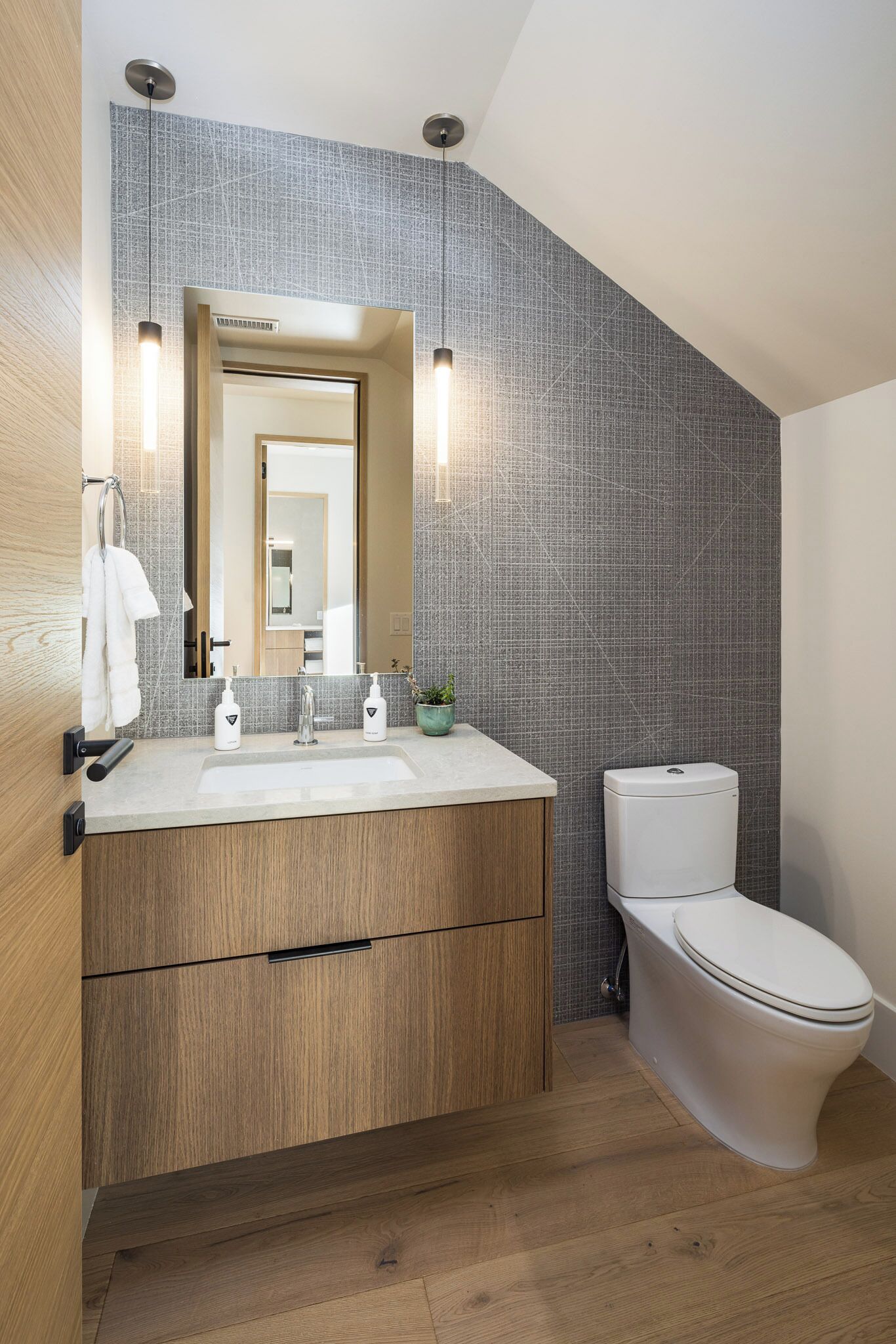 A modern bathroom with a wooden vanity, a white toilet, and a tiled backsplash.