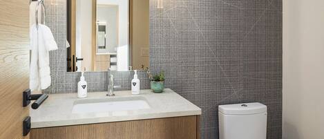 A modern bathroom with a wooden vanity, a white toilet, and a tiled backsplash.