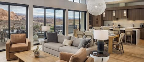 A spacious living area with a large window overlooking a scenic landscape, a cozy seating arrangement, and a modern kitchen with wooden cabinets.