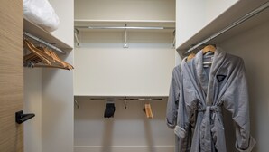 A walk-in closet with wooden flooring, a robe hanging on a rack, and a white plastic bag on the top shelf. - Lionsback Resort (Moab)