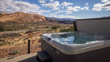 Un jacuzzi con vistas despejadas a un paisaje desértico y montañas al fondo.
