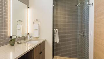 A modern bathroom with a glass-enclosed shower, a vanity with a mirror, and a window providing natural light.