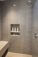 Un baño con ducha, lavabo y un estante con artículos de aseo.